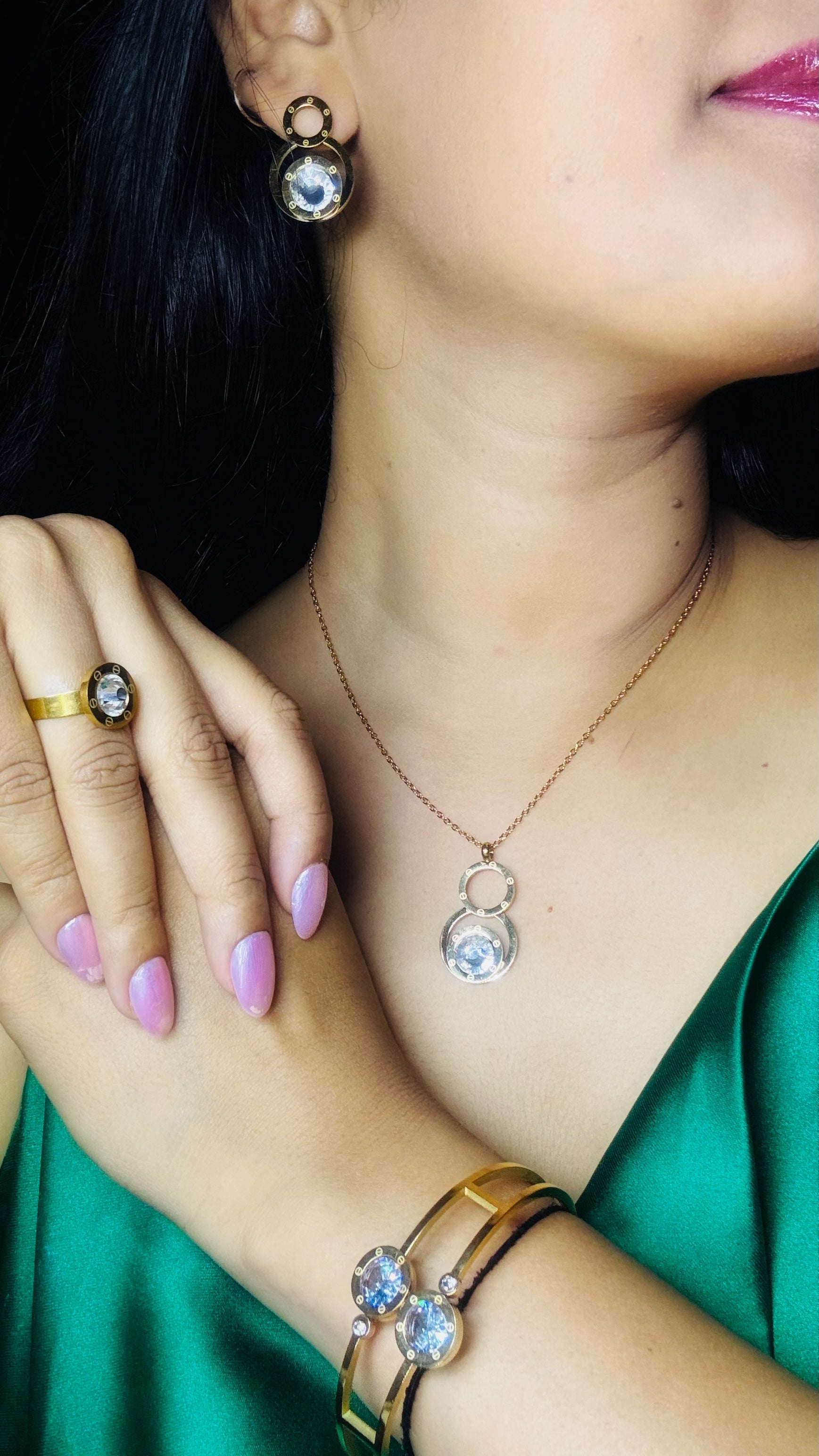 Close-up of a person wearing jewelry including earrings, a necklace, and rings.
