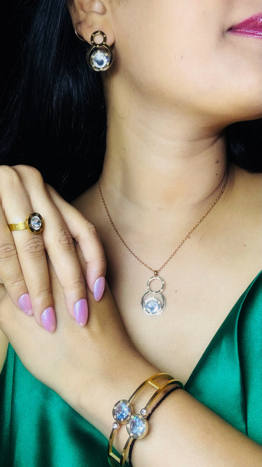Close-up of a person wearing jewelry including earrings, a necklace, and rings.